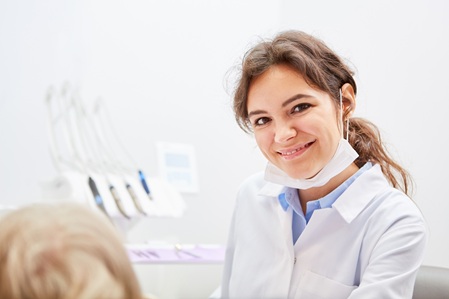 Zahnmedizinische Mitarbeiterin am Behandlungsstuhl mit Patient